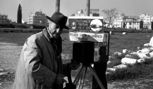 bianconero, cappello, fotografo, anziano, uomo, cavalletto, erba, case, cartello, fotocamera, pietre, prato, cappotto, alberi, vecchio, palazzi, sassi, paese, scritta, massi