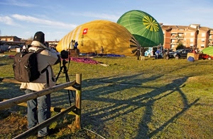 mongolfiere, zaino, fotografo, cielo, prato, staccionata, ombra, verde, ombre, giallo, nuvole, fotocamera, uomo, cavalletto, legno, palazzi, case